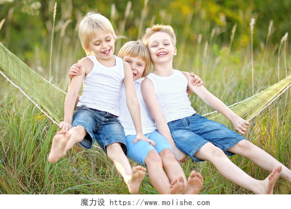 草地上玩耍吊床上的三个外国孩子幸福幸福童年孩子幸福的人美好童年微笑的小孩